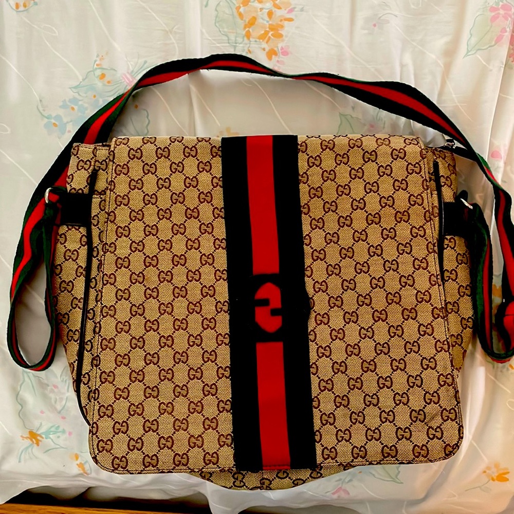 This is a Gucci bag that has a green and red strap with multiple compartments.